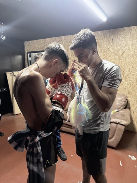 Jayden Gill bowing while his coach blesses the mongkol backstage