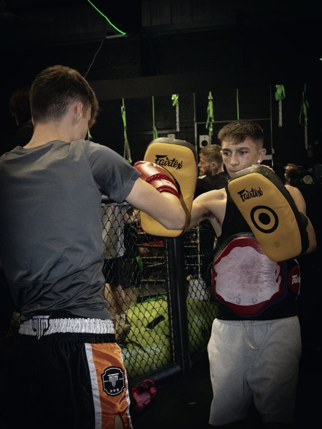 Jayden Gill holding Thai pads for a training partner